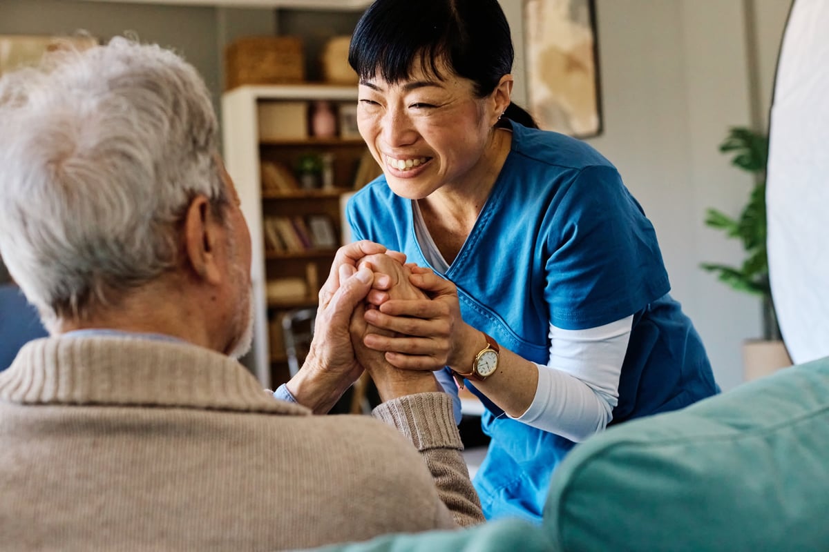 A caregiver comforting a senior, holding hands